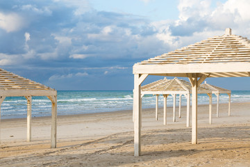 White sunshades on beautiful beach and cloudy sky. Travel and vacation concept.