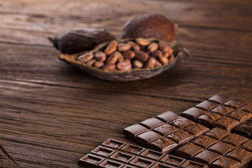 Dark homemade chocolate bars and cocoa pod on wooden