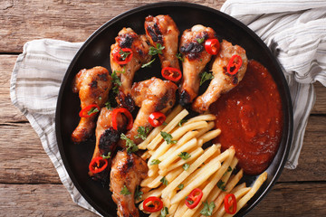 Spicy BBQ chicken wings with french fries and sauce close-up. horizontal top view