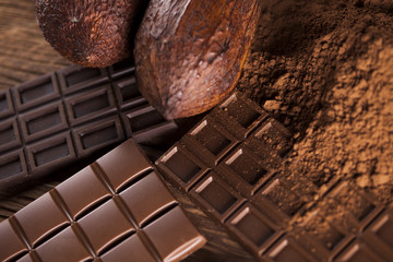 Chocolate bar, candy sweet, cacao beans and powder on wooden background