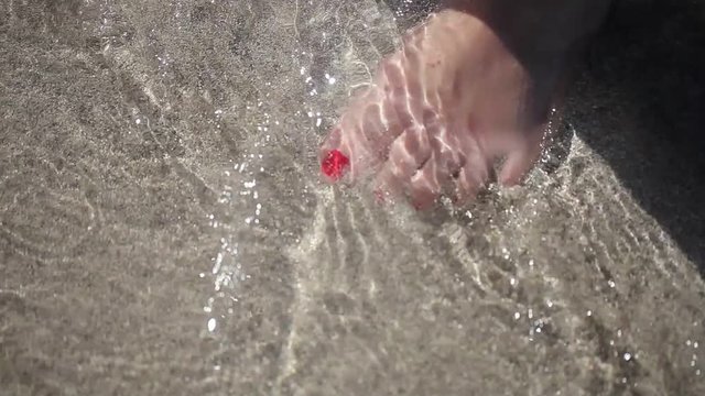 Woman staying in surf on a beach closeup