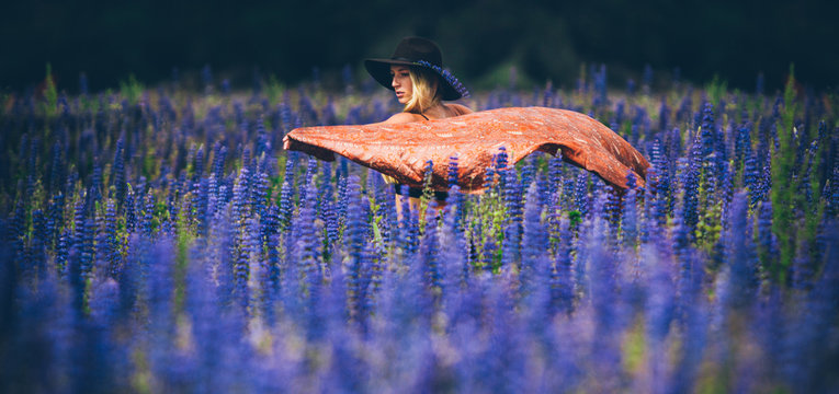 Woman in field with blue flowers and blanket