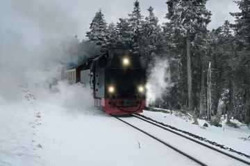 historic steam train driving through snow covered forrest
