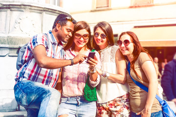 Happy multiracial group of friends looking tour city information on mobile phone - Multicultural students searching street map on smartphone app - Concept of tourism and new technologies