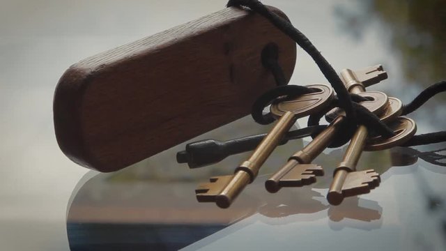 Close Up on Bronze Keys tied with string to wooden key fob