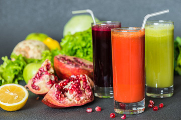 three glasses of different fresh juice. Beet, carrot and kiwi juices on grey background