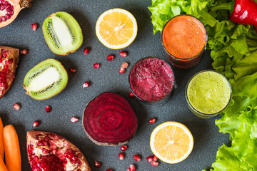 three glasses of different fresh juice. Beet, carrot and kiwi juices on grey background