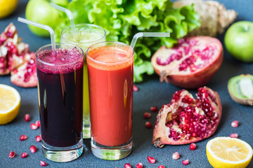 three glasses of different fresh juice. Beet, carrot and kiwi juices on grey background