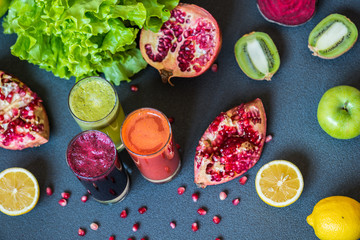 three glasses of different fresh juice. Beet, carrot and kiwi juices on grey background