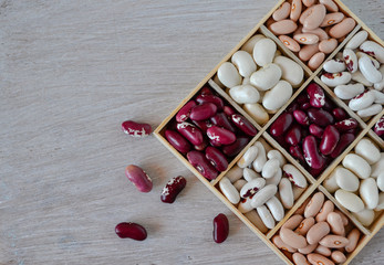 Assortment of beans in wooden box on white wooden background 