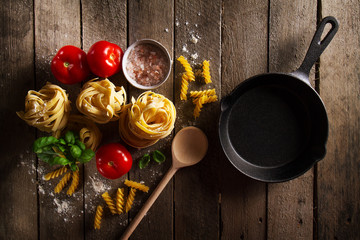 Tasty Fresh Colorful Ingredients for Cooking Pasta Tagliatelle with Fresh Basil and Tomatoes. Top View. Wooden Table Background.