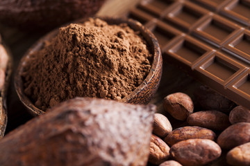 Chocolate bar, candy sweet, cacao beans and powder on wooden background