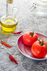 ripe tomatoes on a plate with salt and chili peppers. pickling concept. Vertical