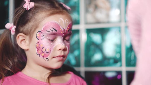 Painter makes butterfly shape at girl's face