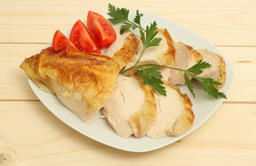 Grilled chicken fillet wit tomato on plate on wood background