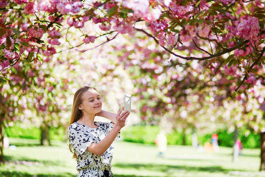 Beautiful young woman in blooming spring park