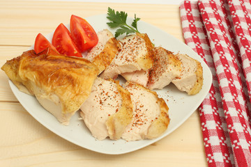 Grilled chicken fillet wit tomato on plate on wood background