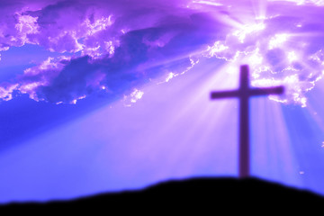 Cross on the Calvary hill with cloudy sky and sun light beams or rays. Abstract blury religious background.