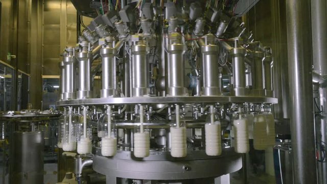 Milk pouring into plastic bottles at a food factory. 4K.