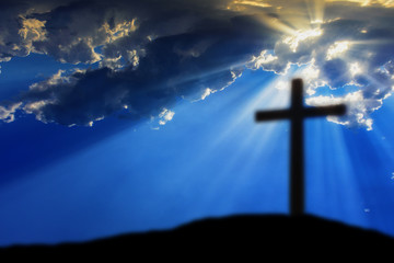 Obraz premium Cross on the Calvary hill with cloudy sky and sun light beams or rays. Abstract blury religious background.
