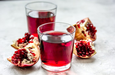 glass of pomegranate juice with fresh slices on stone background