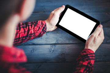 Man in red shirt holding blank screen empty copy space tablet over blue wooden table.