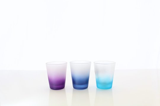 Three Shotglasses Standing in a Row with a Blurry White Background