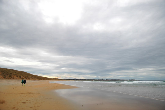 Two Ladies Walking Along A Deserted Beach In Fraserburgh, Scotland