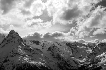 Black and white view on winter snow mountains and cloud sky in evening