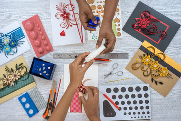 paperquilling art work. two female hands designing paper quilling handicraft. top view.