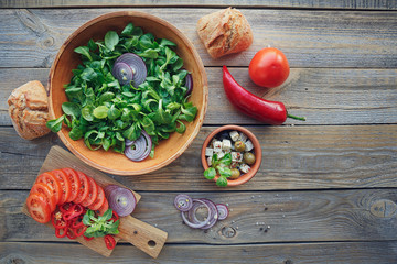 Ingredients for vegetables salad on a wooden background.