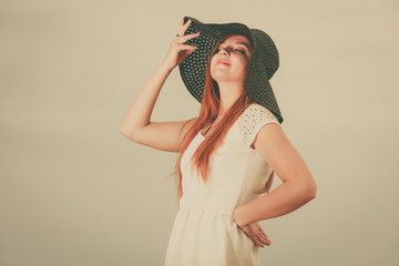 Happy redhead woman wearing big black sun hat