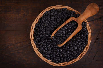 Black beans in scoop on wooden background