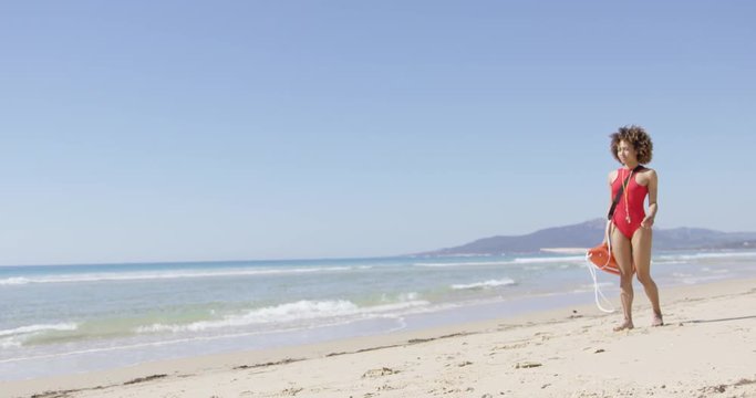 Lifeguard female with rescue float walking on beach and looking into distance. Tarifa beach. Provincia Cadiz. Spain. 