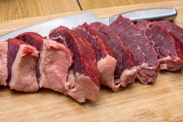 Fresh raw sliced meat beef on an wooden cutting board.