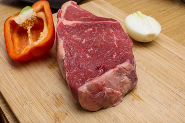 Raw beef on a wooden cutting board. Wooden background