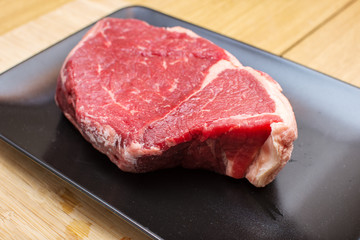 Raw beef on a black plate.