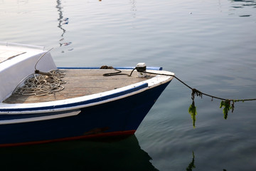 Small traditional fishing boat in a port. Detail of a nautical rope with seaweed. Selective focus. 