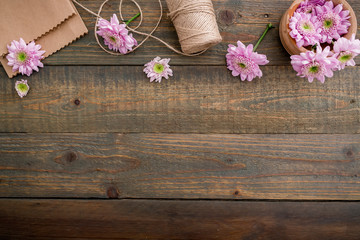 Pink flowers and twine, craft paper on wood background. Flat lay, top view. Woman's background
