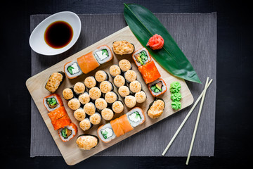 Japanese food - sushi rolls and sauce on black background. Top view. Flat lay