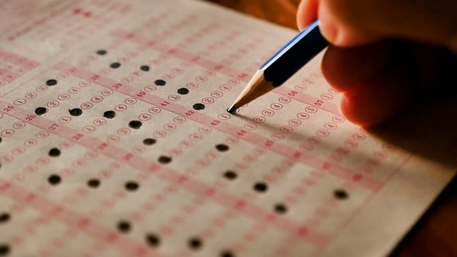 Student using pencil filling select choice on answer sheets slow motion shot