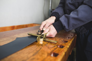 Close up shot of worker's hands in leather belt making process. Selective focus on worker's hand.