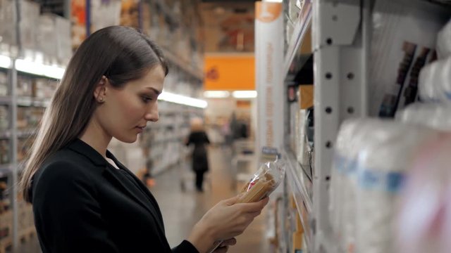 Woman choosing pasta in grocery store. Brunette shopping in food supermarket
