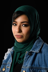 Portrait of a beautiful Muslim woman dressed in hijab on a black background in photo studio.