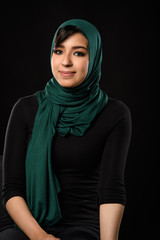 Portrait of a beautiful Muslim woman dressed in hijab on a black background in photo studio.