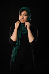 Fototapeta premium Portrait of a beautiful Muslim woman dressed in hijab on a black background in photo studio.