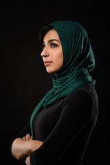 Portrait of a beautiful Muslim woman dressed in hijab on a black background in photo studio.