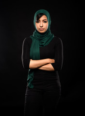 Portrait of a beautiful Muslim woman dressed in hijab on a black background in photo studio.