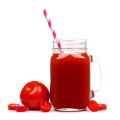Mason jar glass of tomato juice with straw and surrounding tomatoes isolated on a white background