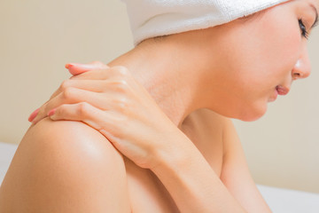 Fototapeta premium Young woman sitting on the bed suffering from pain in shoulder